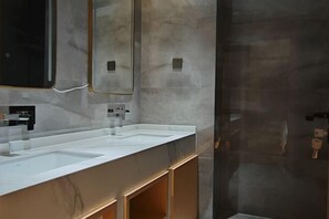 Une salle de bain moderne avec un grand miroir, deux lavabos et un espace douche.