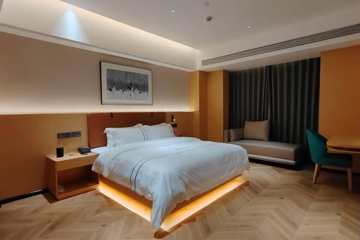 Un hotel moderno con cama, mesita de noche, sillón y vistas al exterior.