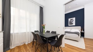 Een moderne kamer met een eettafel, stoelen, een bed en een nachtkastje.