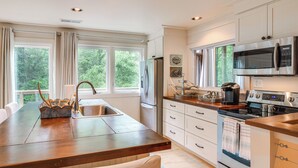 Een moderne keuken met een centraal eiland, roestvrijstalen apparatuur en grote ramen.