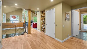 A spacious interior with a wooden floor, a staircase, and a view of greenery outside. - Lakefront Roxboro Home w/ Private Dock! (Roxboro)