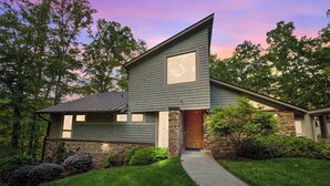 A modern two-story house with a stone foundation, a large window, and a well-maintained lawn. - Lakefront Roxboro Home w/ Private Dock! (Roxboro)
