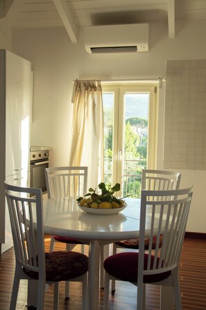 A dining area with a round table, four chairs, and a bowl of fruit.