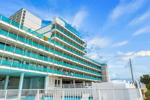 A multi-story hotel with a swimming pool and a parking garage.