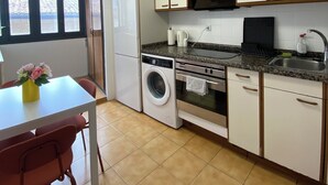 Une cuisine compacte équipée d’un lave-linge, d’un four et d’un coin repas avec une table et des chaises.