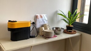 Une petite cuisine équipée d’une machine à café, d’une pile d’assiettes, d’un bol et d’une plante en pot.