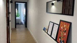 Un couloir avec des poutres en bois au plafond, un mur blanc orné d’un grand miroir et des œuvres d’art encadrées.