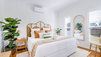 A bedroom with a bed, bedside table, lamp, and a large mirror.