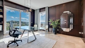 Een moderne kantoorruimte met een glazen tafel, bureaustoelen, een potplant en een grote spiegel aan de muur.