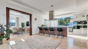 Een moderne keuken met een groot schiereiland, barkrukken en een eethoek met uitzicht.