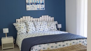 A bedroom with a bed, bedside tables, a hanging light fixture, a bench, and a painting on the wall. - La Casa de Babou (Le Château-d'Oléron)