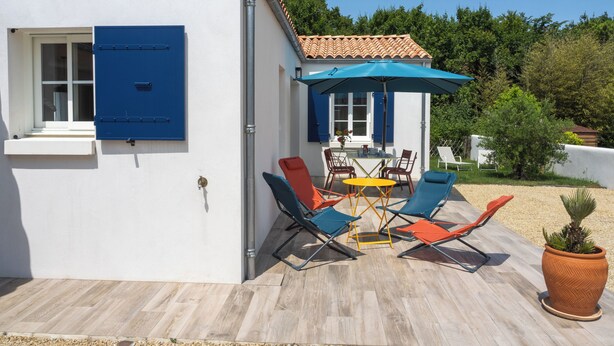 A patio with outdoor furniture, a table, and a blue umbrella. - La Casa de Babou (Le Château-d'Oléron)