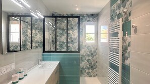 A modern bathroom with a large mirror, a bathtub, a shower, and a built-in towel rack. - La Casa de Babou (Le Château-d'Oléron)