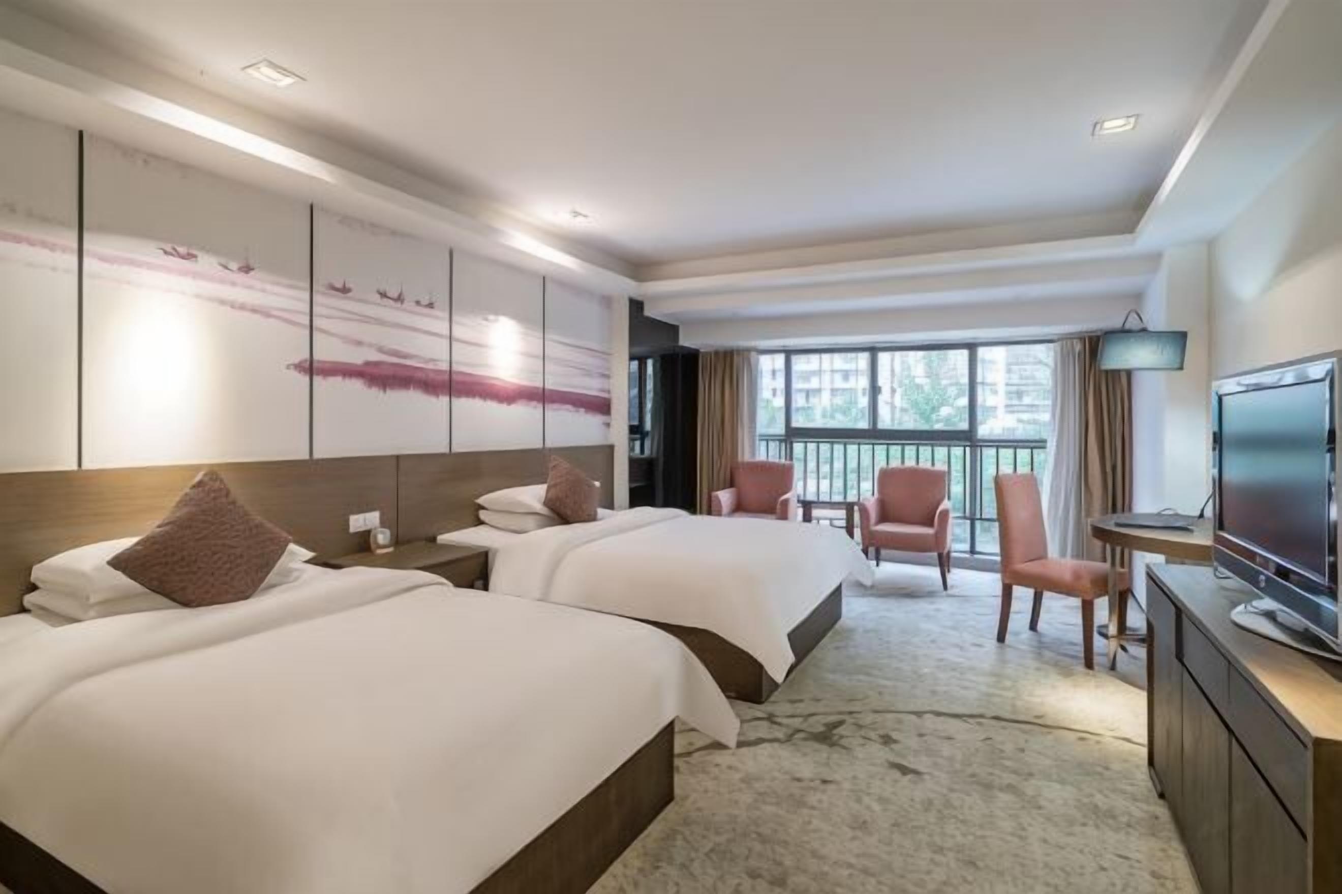 Ein Hotelzimmer mit zwei Betten, einem Fernseher, einem Schreibtisch und einem Balkon mit Blick.