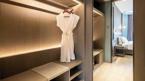 Une chambre d’hôtel moderne dotée d’un dressing, d’un banc et d’un miroir.
