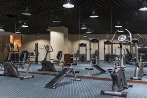 Un gimnasio con equipo de ejercicio, espejos y piso estampado.