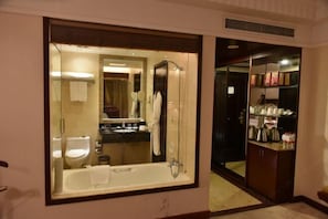 A bathroom with a large mirror, a bathtub, a toilet, and a sink.