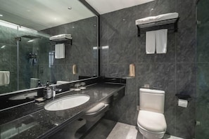 A modern bathroom with a large mirror, a sink, a toilet, and a shower area.
