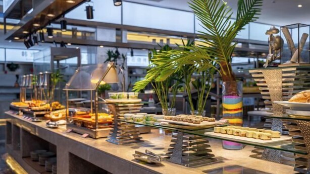Un buffet proposant une variété de plats et agrémenté d’une plante décorative, comme un palmier.