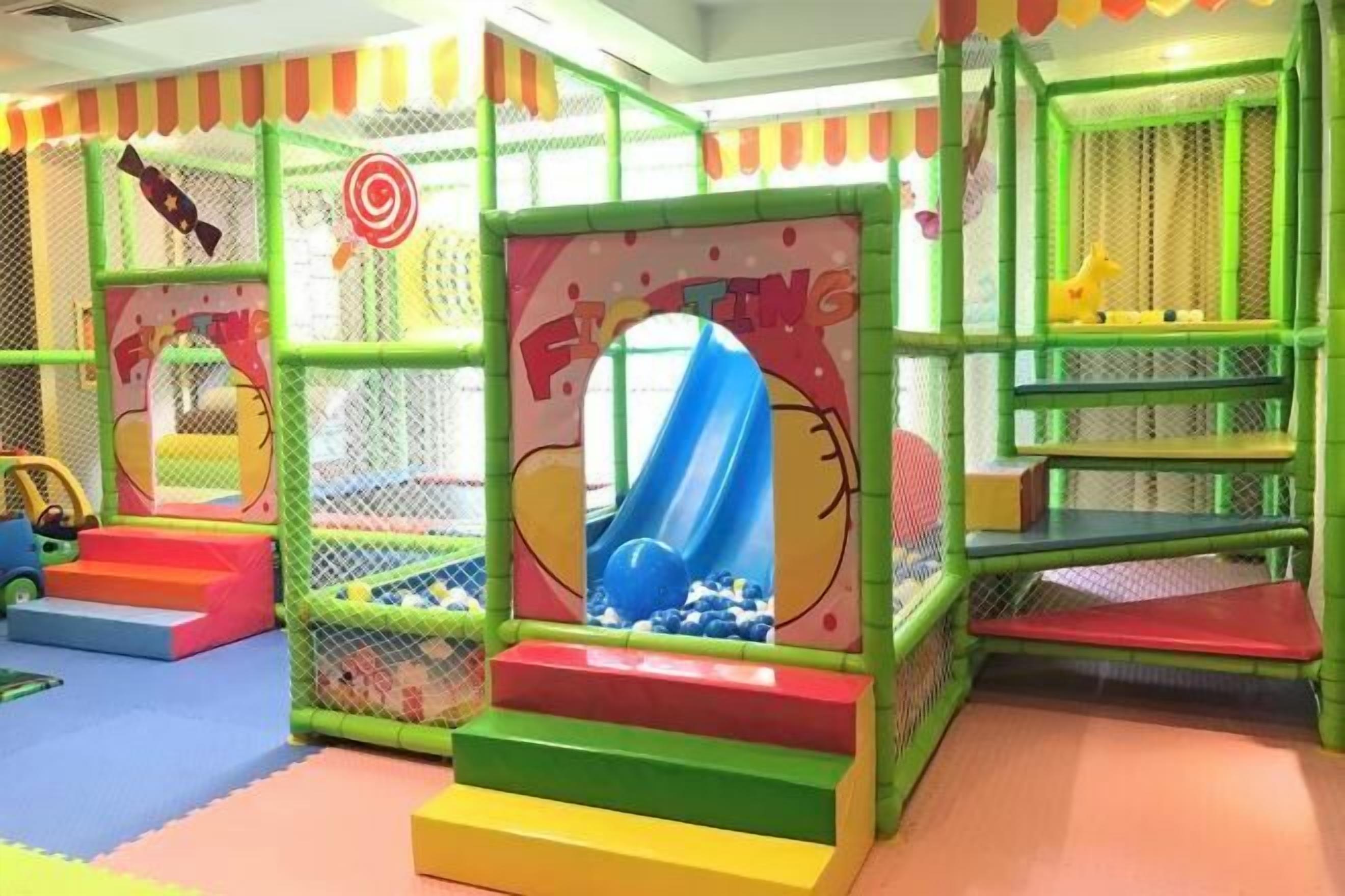 Un área de juegos infantiles con un tobogán, escaleras de acceso y una piscina de pelotas.