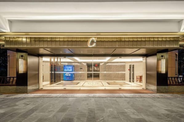 A hotel entrance with a modern design, featuring a prominent 'C' logo, glass doors, and a reception area with a blue counter. - Luxury Blue Horizon Hotel (Wuxi Huishan Wanda Plaza) (Wuxi)