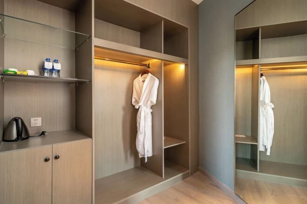 A walk-in closet with multiple shelves and hanging space, a kettle, and a few toiletries on a shelf.
