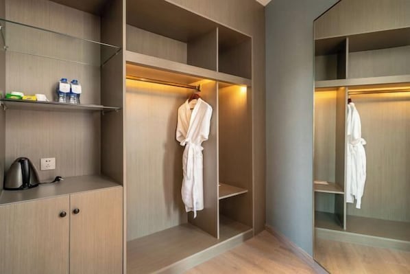 A walk-in closet with multiple shelves and hanging space, a kettle, and a few toiletries on a shelf.