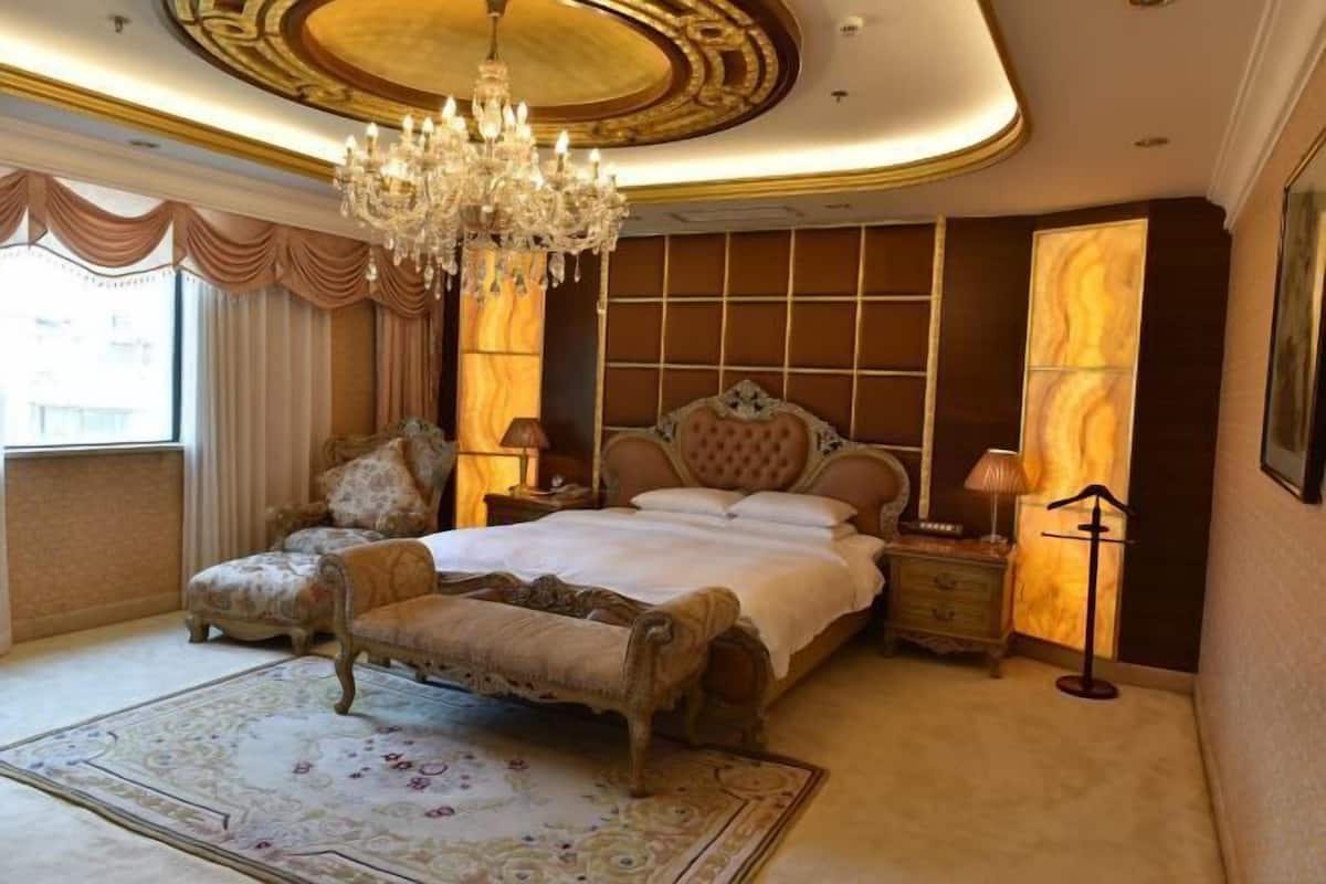 A luxurious bedroom with a large bed, ornate chandelier, and classic furniture.
