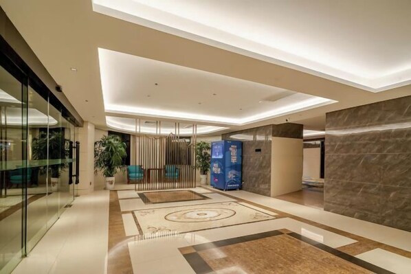 Een moderne hotellobby met glazen wand, een receptiebalie en een vloer met een patroon.
