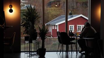 Un comedor acogedor con un ventanal grande, plantas en macetas y un edificio rojo al fondo.