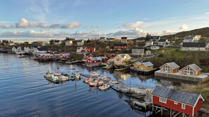 A harbor with boats docked, wooden houses, and a red building on stilts. - The Tide - Hotel (Moskenes)