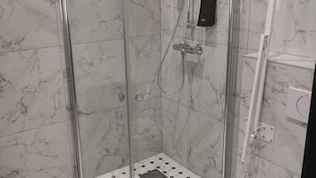 A modern bathroom with a glass-enclosed shower, a white toilet, and a tiled floor with a hexagonal pattern.