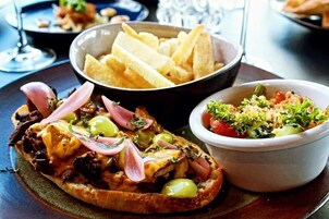 Un plato con pan relleno, un tazón de papas fritas y una ensalada.