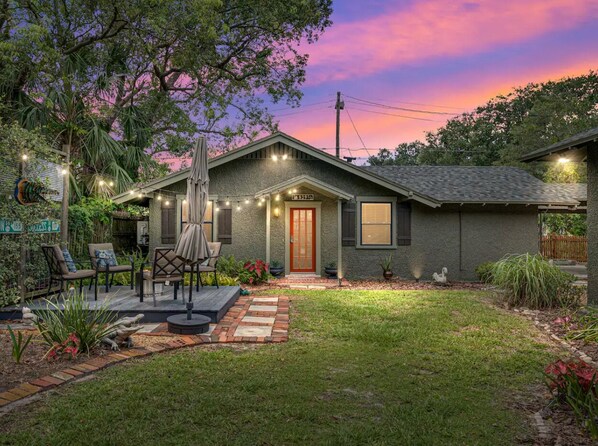 A house with a front porch, outdoor seating, and a well-maintained garden.