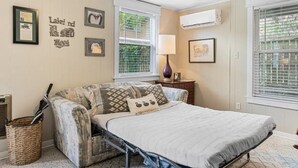 Une chambre confortable avec un lit, une petite table, une lampe et des tableaux encadrés accrochés au mur.
