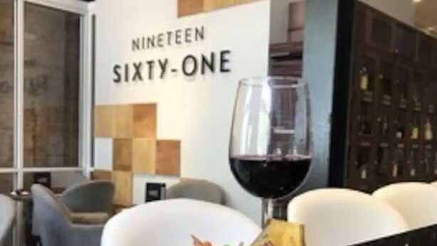 Un coin repas avec une table mise pour le dîner, un verre à vin et un mur sur lequel on peut lire le texte « NINETEEN SIXTY-ONE ».
