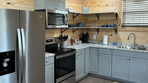 A modern kitchen with stainless steel appliances, grey cabinets, and wooden ceiling. - Rattletrap Cabin - 3bed/2bath (Scottsboro)
