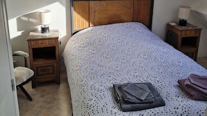 Un dormitorio con una cama, una mesita de noche, una silla y una pequeña mesa.