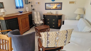 Una sala de estar con sofá, sillón, aparador de madera y una mesa de comedor.