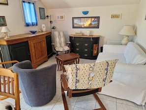 Una sala de estar con sofá, sillón, aparador de madera y una mesa de comedor.