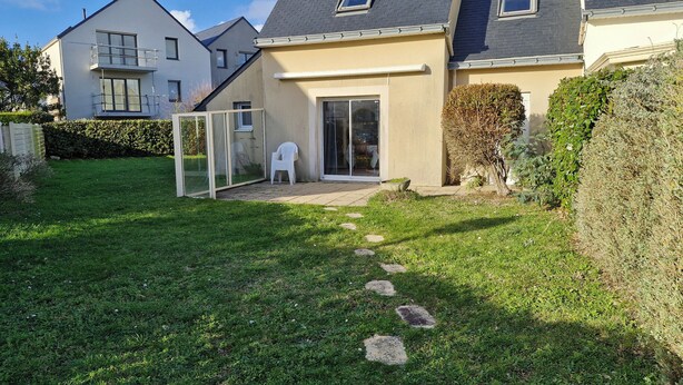 Una propiedad residencial con un césped cuidado, un patio y una entrada con puerta corredera de vidrio.