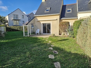A residential property with a well-maintained lawn, a patio area, and a sliding glass door entrance.