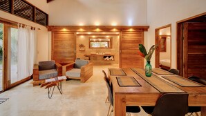 Un vaste espace de vie comprenant une table à manger en bois, des sièges confortables et une cuisine à l’arrière-plan.