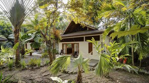Een tropisch resort met een houten huis, omringd door weelderige begroeiing en palmbomen.