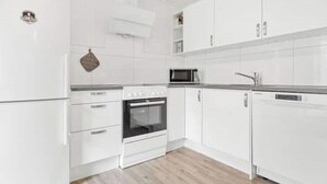 Une cuisine moderne avec des meubles blancs, un four à micro-ondes, un four traditionnel et un lave-vaisselle.