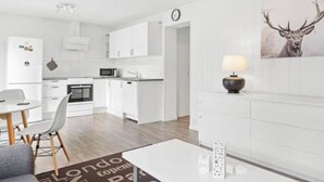 Une cuisine moderne avec des meubles blancs, un four à micro-ondes et une horloge au mur.