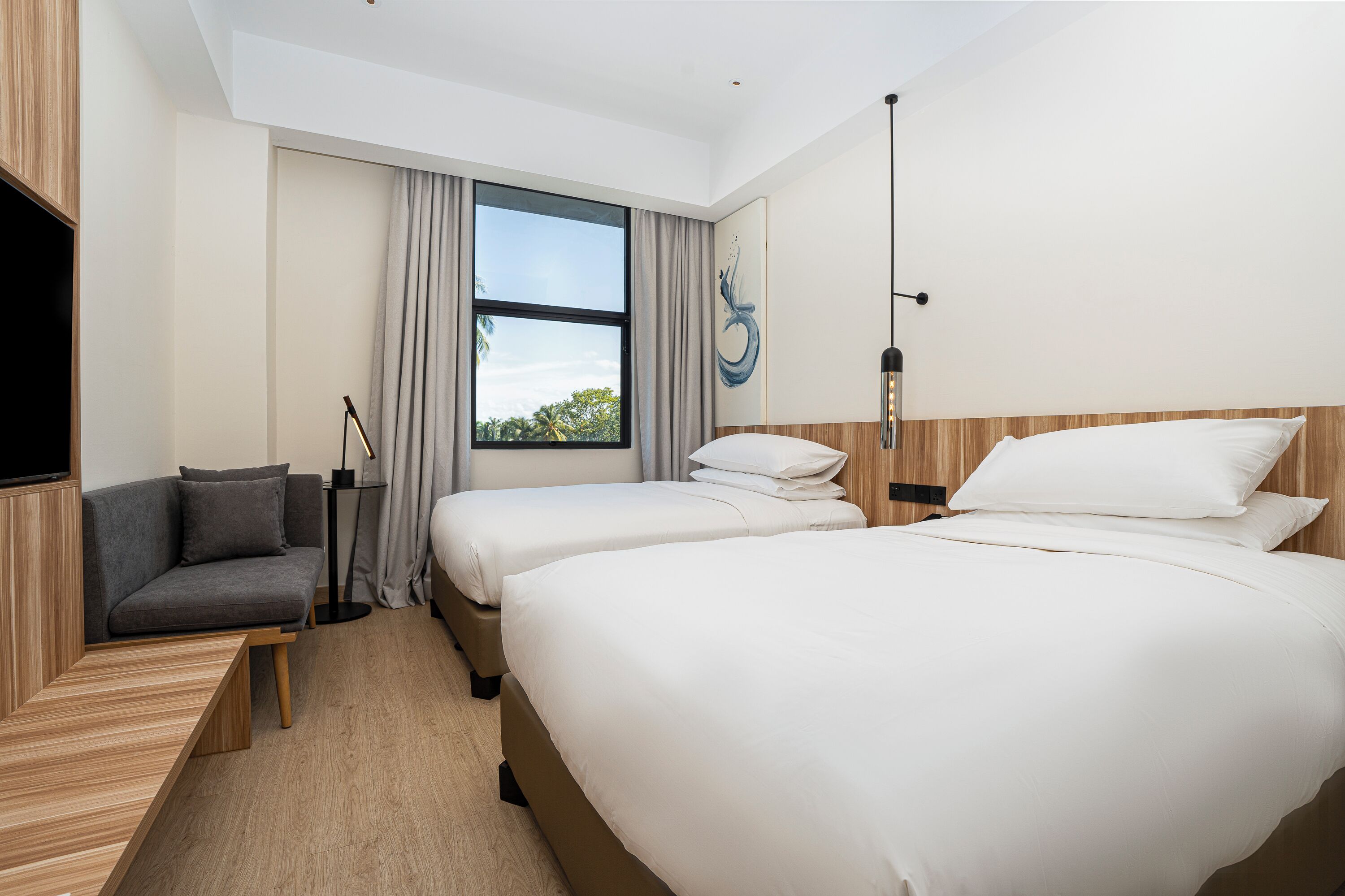 A hotel room with two beds, a sofa, a TV, and a window with curtains.