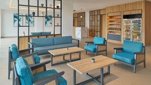 A modern lounge area with seating, a coffee table, and a decorative wall with shelves. - Fairfield By Marriott Kuala Besut (Kampong Raja)