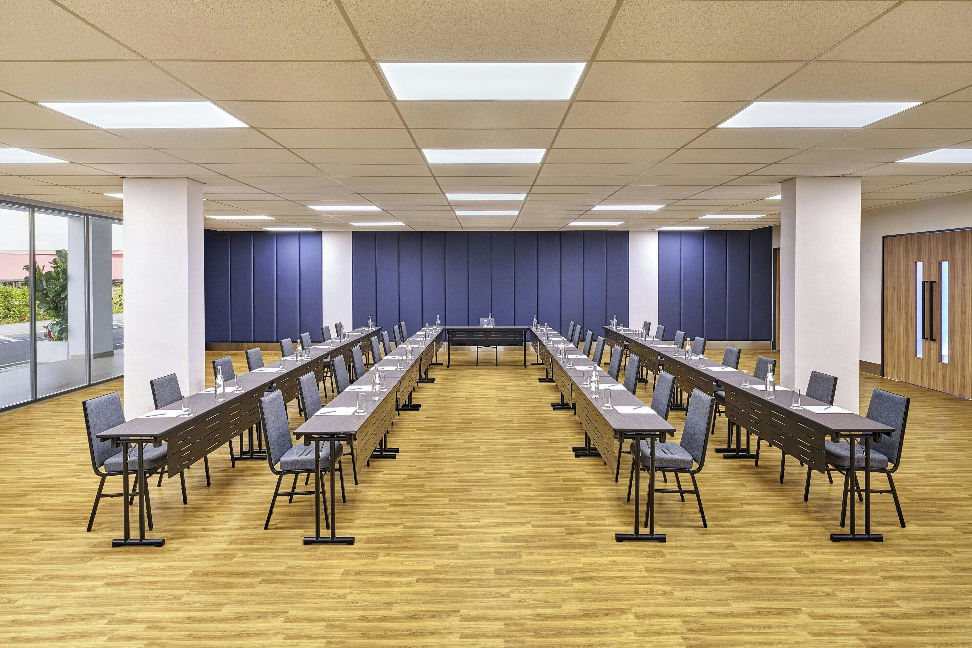Ein Konferenzraum mit einem langen Tisch, Stühlen und einer neutralen Farbgebung.