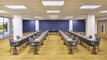 Un salón de conferencias con una larga mesa, sillas y una decoración en tonos neutros.